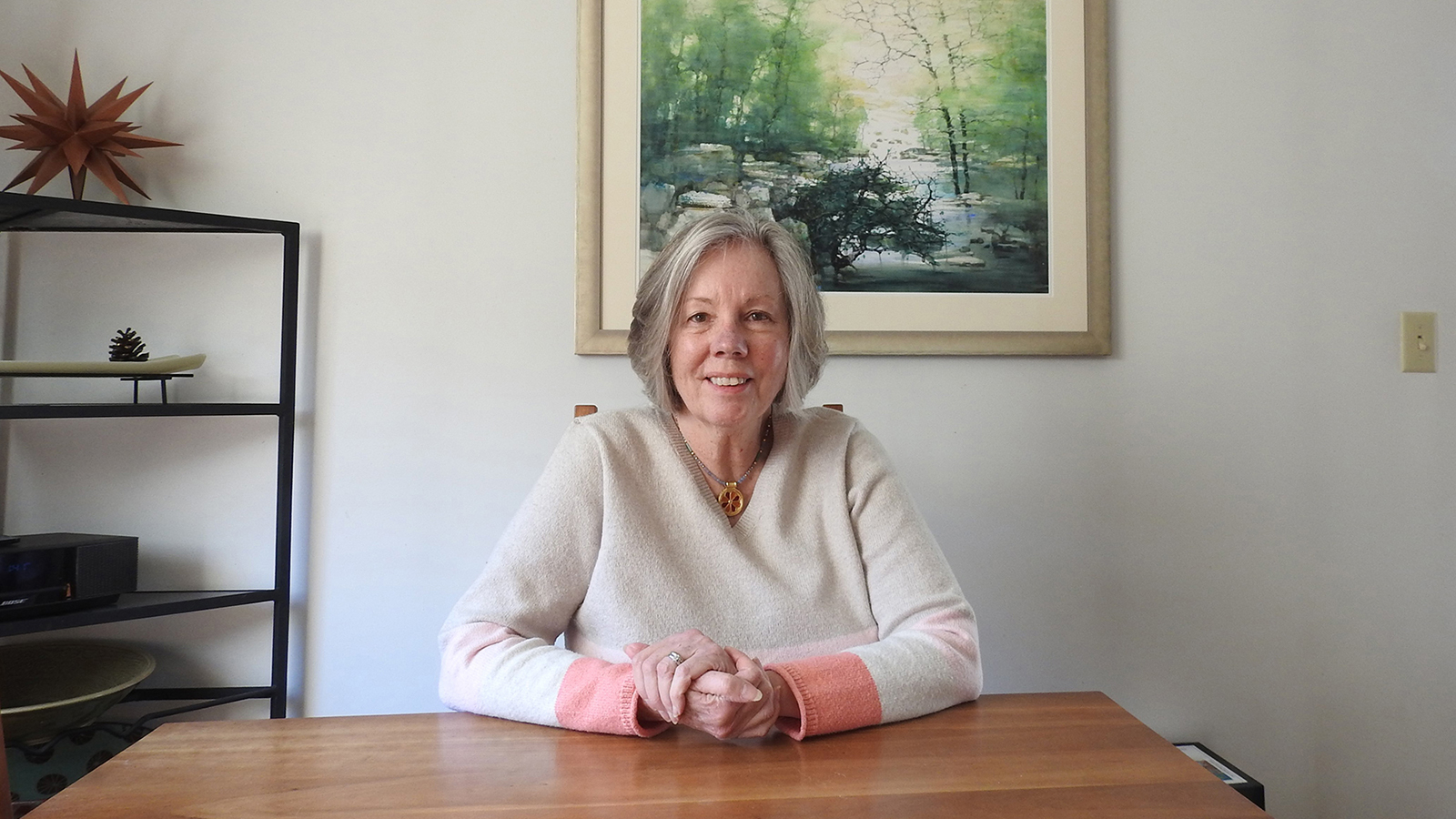 Alice Clark sitting at a table with artwork behind her