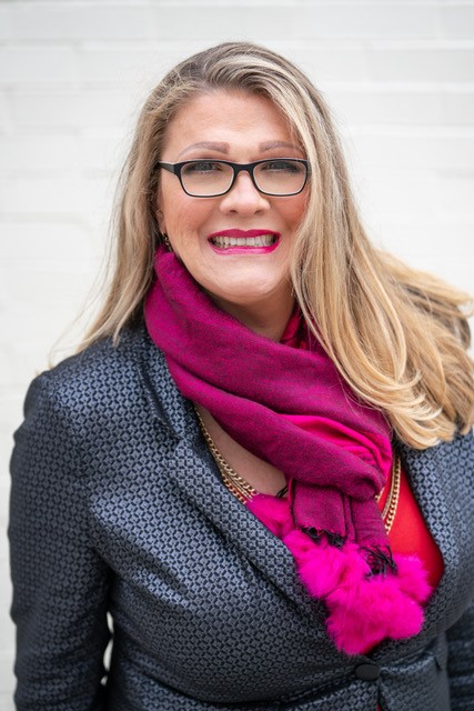 Dr. Stacee L. Reicherzer with glasses and long blonde hair, wearing purple scarf and gray jacket.