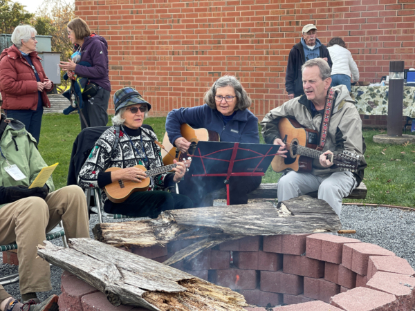 People playing guitars around a firepit.