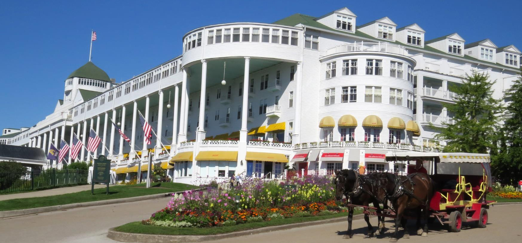 Large white historic hotel with a horse and carriage in front