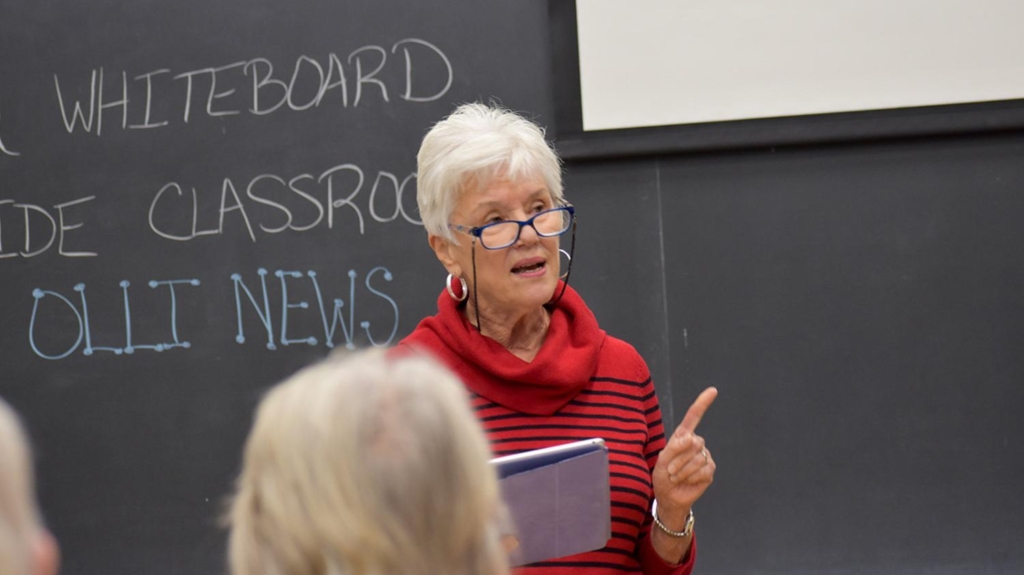Woman with glasses speaking in a classroom