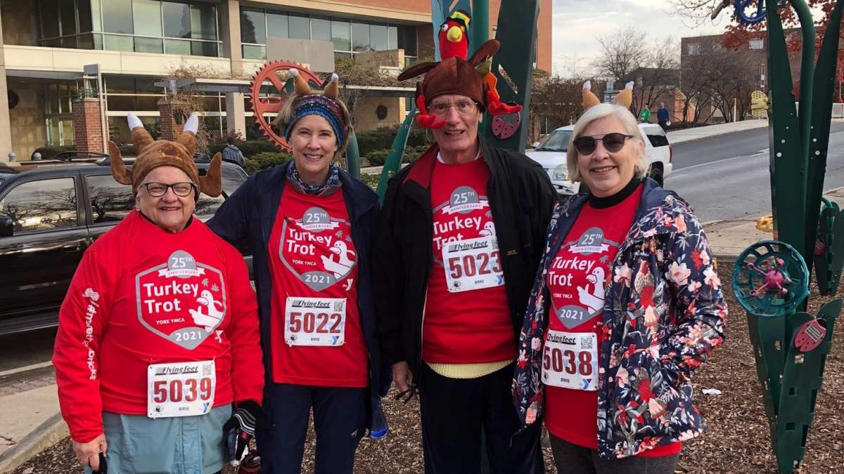 Four people wearing red shirts and turkey hats