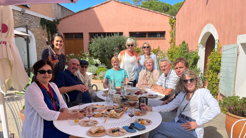 OLLI members sit outside on a patio, enjoying wine and food