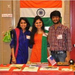 Participants at International Day stand behind a table of cultural information.