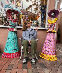 Jan Tucker sits on a chair outside a shop in Santa Fe, New Mexico, and admires colorful sculptures